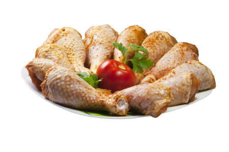 Chicken legs with tomato on plate and white backgroundの写真素材