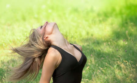 Portrait of young woman with wind blowing hair in the parkの写真素材