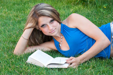 Beautiful girl lies on meadow and reads the book の写真素材
