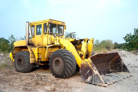 Old wheel loader bulldozer with bucket standing in sandpit outdoorsの写真素材
