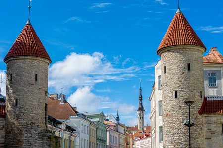 The medieval Viru Gate towers stand at the entrance to Tallinnâs Old Town, framed by colorful historic houses and the Town Hall spire rising in the background.の写真素材