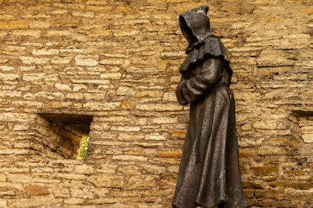 Hooded monk statue standing on a medieval stone wall in the Danish Kingâs Garden, Tallinn old town, Estonia, representing history, culture, and mystery.の写真素材