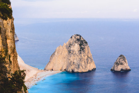 Majestic limestone peaks known as Mizithres rise from the turquoise Ionian Sea next to a white beach at Cape Keri, Zakynthos. Aerial-like view of natural coastal beauty.の写真素材