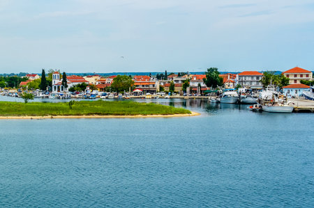 Seaside village with red-roofed houses, docked fishing boats, and a white church, seen from a ferry...