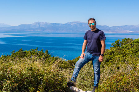 Man posing casually in front of the sea with a stunning view of Corinthian Gulf and mountains in...