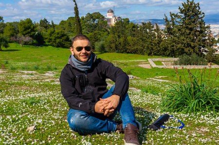 Man sitting on meadow at Pnyx Hill with Athens Observatory, Greece.の写真素材