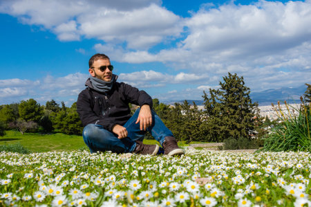 Man sitting in flower meadow at historic Pnyx Hill with Athens view.の写真素材