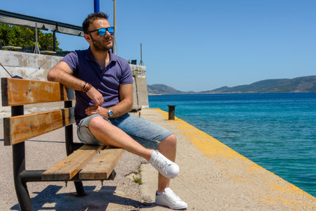 Man with sunglasses sitting by the sea in Pachi, Greece.