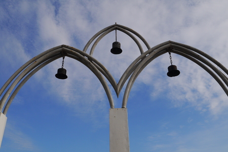 Arch entrance with bells on the foot bridge through the riverの写真素材