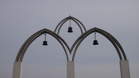 Arch entrance on the pedestrian bridge with the bells suspended on a chainの写真素材