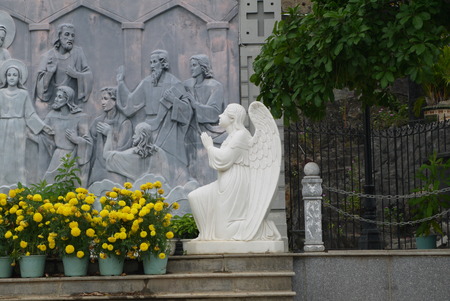 Sculpture of a kneeling angel at a wall with plots on a biblical themeの写真素材