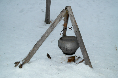 The marching kettle is suspended on a hook on a tripod in a winter campaignの写真素材