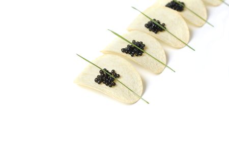 Black caviar with spring onion on potato chipsの写真素材
