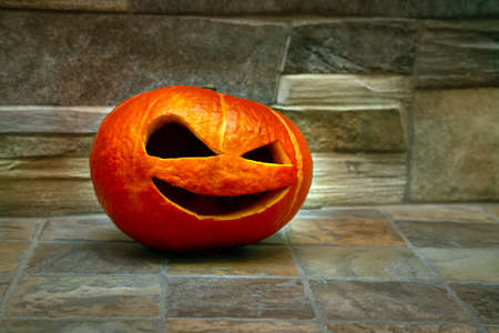 Halloween pumpkin stands on a green carpet against a stone wall. Jack o` lanternの写真素材