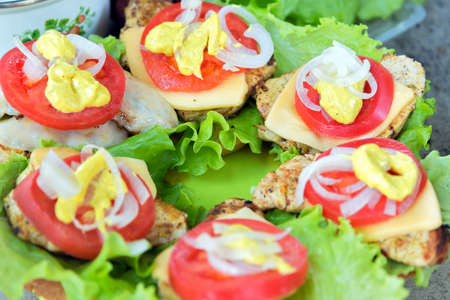 Bbq meat with cheese, tomatoes, onions and lettuce. On a roll and green plastic boardの写真素材