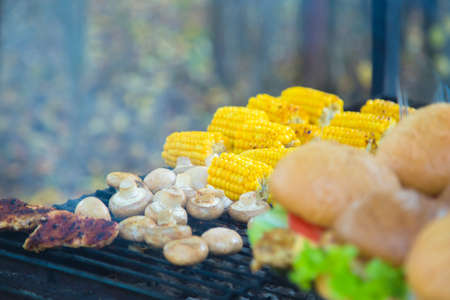 Burgers and corn cooked outdoors on grill