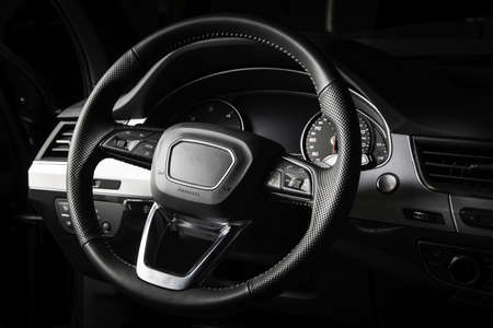 Dark luxury car interior. Black leather multifunctional steering wheel, start and stop engine buttom, dashboardの写真素材
