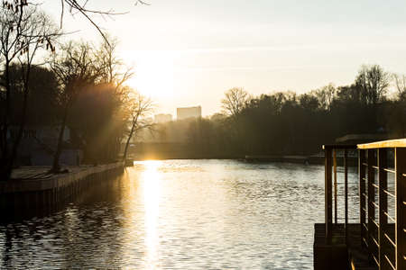 Pier on the lake in the city park. Autumn sunset, a beautiful sun path on the water