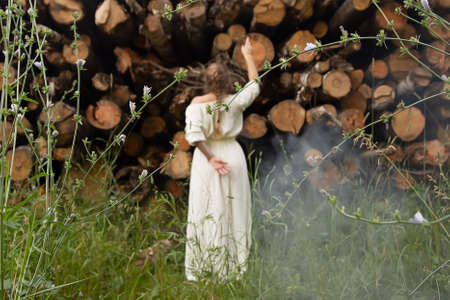 Unfocused. Stop deforestation. Girl stands in front of sawed down trees looking at them with regret. Take care and save nature. Background of cut down trees, logs in the forestの写真素材