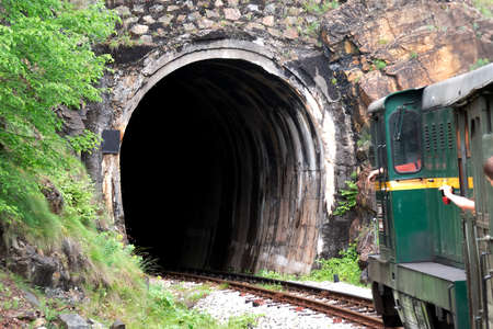 train with pasengers going to the tunnel in the mountainの写真素材