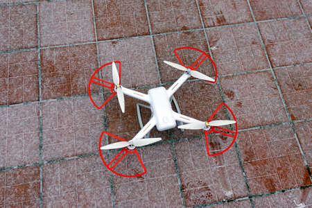 A quadrocopter drone stands in the snow on a red-brown tile. ready to fly in winterの写真素材