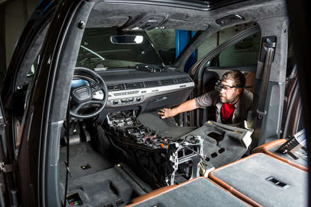Moscow. November 2018. A mechanic repairs an Audi SUV Repairing wiring, gearboxes, disassembled interior premium crossover. Removed chairs. Leather interior. Neat repair service center.のeditorial素材