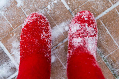 Red felt boots covered in snow. On the red orange tileの写真素材