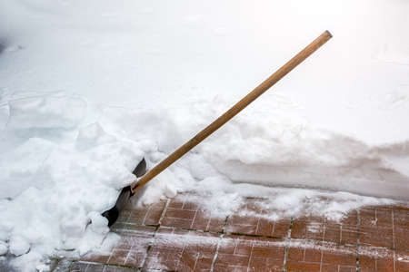 Big black plastic shovel with wooden handle drive in snowdrift. Cleaning snow from backyard after heavy winter snowfallの写真素材