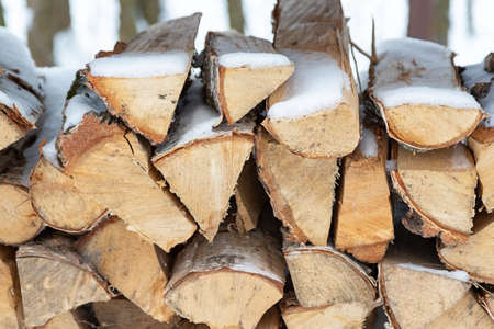 Chopped stock of firewood under snow on the street. Firewood for fireplace and bbqの写真素材
