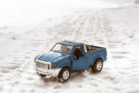 Toy blue pickup car in winter forest. Stands on the road. In the back of pickup truck are Christmas tree cones.の写真素材