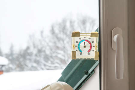 Old round plastic thermometer outside on the window. Shows minus four degrees on the streetの写真素材