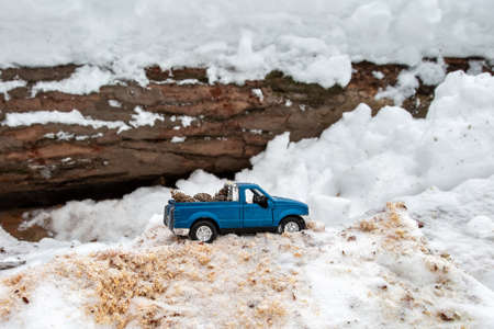Blue toy pickup truck in sawmill. Stuck at snowdrift and sawdust. Carrying a car body.の写真素材