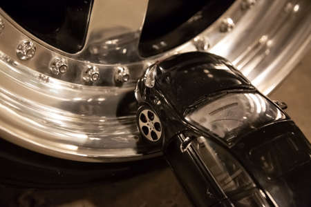 Black toy car stays on alloy rims of real car. Custom tuning wheelsの写真素材