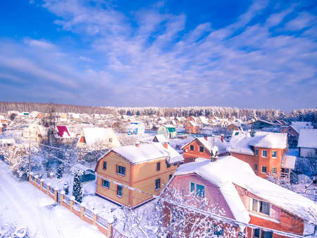 Village in forest. Winter aerial view. Blue cloudy sky.の写真素材