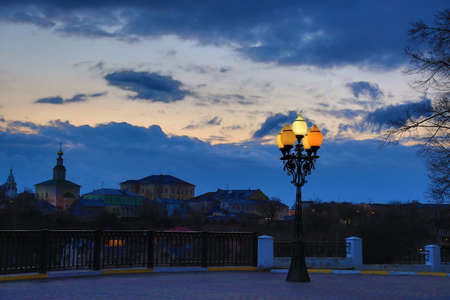 Street lamp on the background of a beautiful sunset sky with clouds. Colorful houses and churchの写真素材