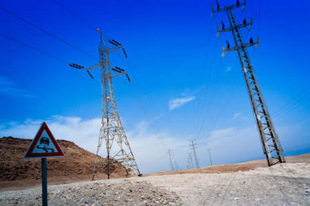 High voltage power lines in the desert area. Road signの写真素材