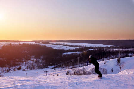 Extreme rides at sunset. Snowboarder down the slope.の写真素材