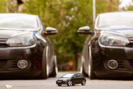 Moscow. Autumn 2018. Two real full size black Volkswagen Golf and a small toy such Golf between...
