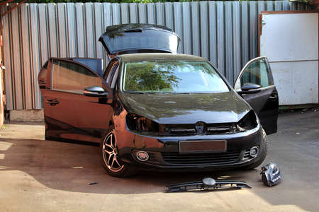Self repair of a car at summer, near garage. Changing headlights. Black hatcback without front headlights and grill of radiatorの写真素材