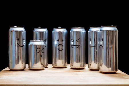 Empty aluminum cans as a human society. Instead faces smilies drawn on the trash. Emoji smile angry...