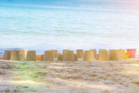 Child made a lot of cone figures made of beach sand. Sunny day and blue water of sea on a background. Summer vacation of kidsの写真素材