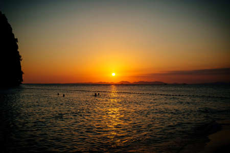 People swim in the sea in the evening at sunset