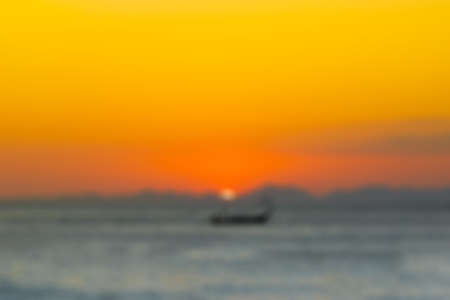 Abstract blurred background Wooden fishing boat sailing on the sea, against the backdrop of the sunset and the mountains.の写真素材