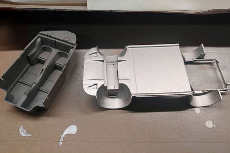 Unprimed and primed parts of a scale model car for assembly. Body and car interior. Modeling....