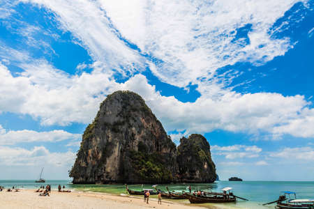 Krabi, Phranang Beach, Thailand - February 12, 2019: PhraNang Cave Beach in andaman sea. Sandy beach with tourists and long-tail boats, mountain and blue sky with cloudsのeditorial素材