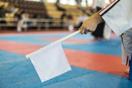 Hand of old man who holds a white flag on the background of the stands