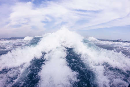Big waves from the motor behind the speedboat on the high seas. Blue sky with white clouds.の写真素材