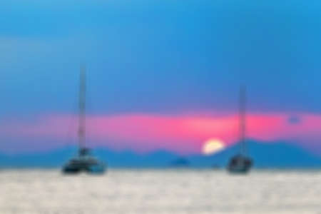Blurred abstract background. Two sailing yachts in the sea. During sunset, the sun sets over the mountains.の写真素材