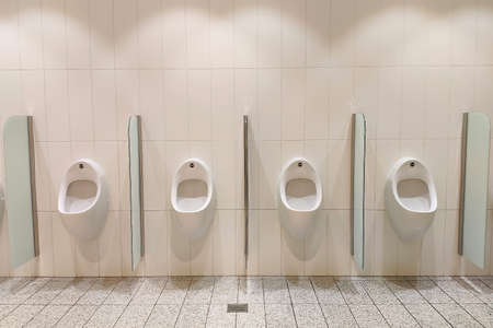 White urinals in the men's room. On the wall, front view.