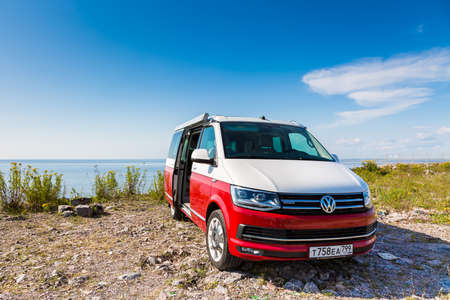 St. Petersburg, Russia - July 22, 2019: Red and white colored modern Volkswagen Multivan California Ocean (Transporter T6).  Is parked on the beach. Front side viewのeditorial素材